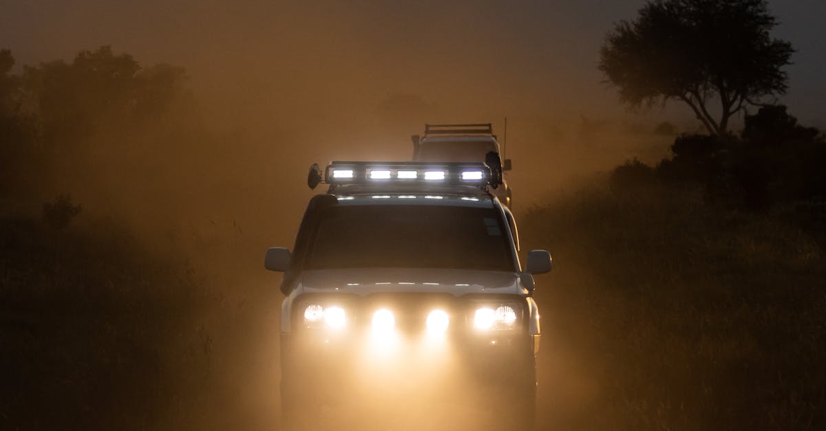 An off-road SUV drives through the dusty savannah of Tsavo, Kenya at sunset.