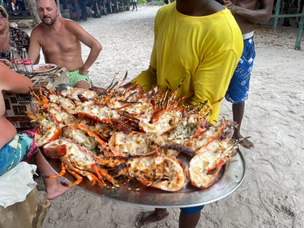 Duża taca grillowanych ryb i owoców morza podana na plaży w Watamu.